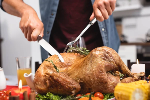 Cropped view of man cutting delicious turkey during thanksgiving dinner — Stock Photo