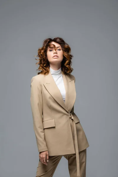 Élégante femme en costume beige posant isolé sur gris — Photo de stock