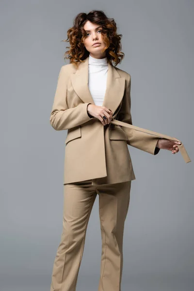 Elegante Frau im beigen Anzug posiert isoliert auf grau — Stockfoto