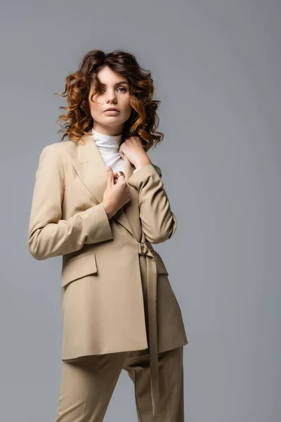 Elegante donna in abito beige posa isolata sul grigio — Foto stock