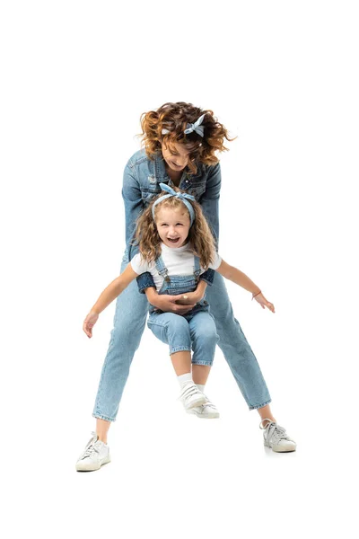 Мать и дочь в джинсовых нарядах веселятся изолированно на белом — стоковое фото