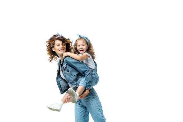 Vista laterale della madre piggybacking figlia in denim vestito isolato su bianco — Foto stock