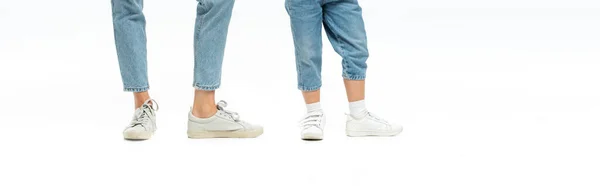 Cropped view of mother and daughter in jeans and sneakers isolated on white, panoramic shot — Stock Photo