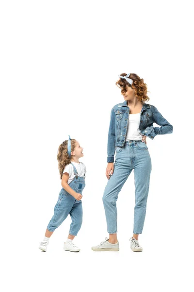 Мати і дочка в джинсових вбраннях дивиться один на одного ізольовані на білому — стокове фото