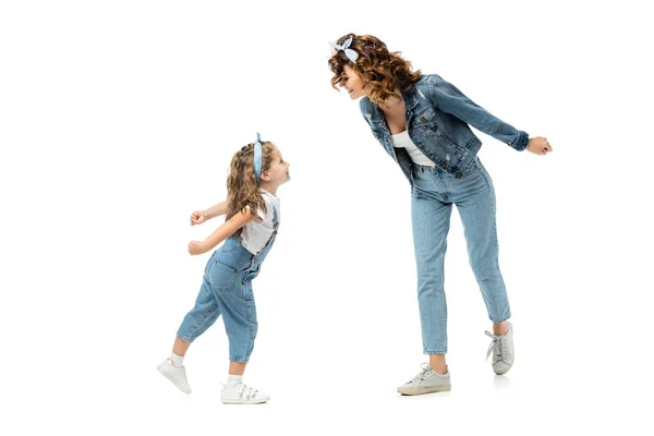 Madre e hija en trajes de mezclilla mirándose aisladas en blanco - foto de stock