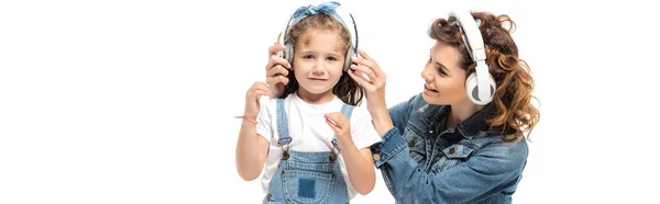 Mother and daughter in denim outfits listening music in headphones isolated on white, panoramic shot — Stock Photo