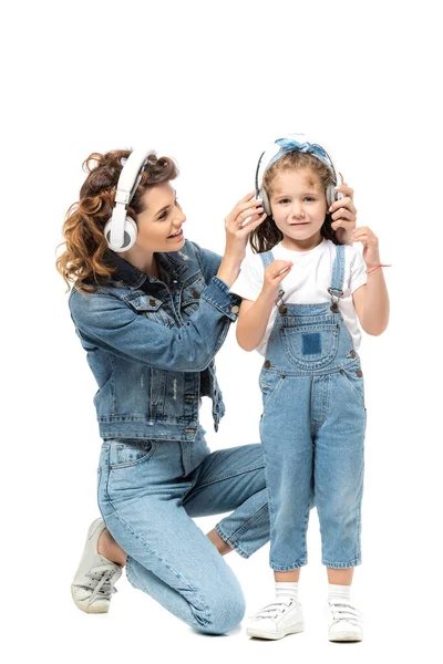 Mutter und Tochter im Jeans-Outfit hören Musik in Kopfhörern isoliert auf weiß — Stockfoto