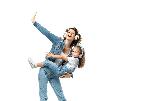 Mother holding daughter and listening music in headphones isolated on white — Stock Photo