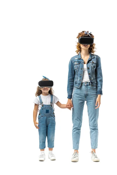 Мати і дочка в джинсових вбраннях і гарнітурах віртуальної реальності, що тримають руки ізольовані на білому — стокове фото