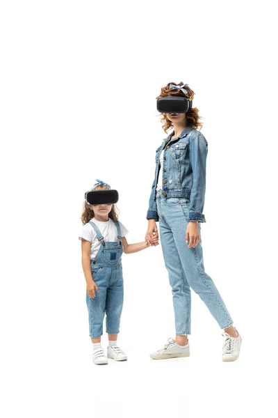 Mãe e filha em trajes de ganga e fones de ouvido realidade virtual de mãos isoladas em branco — Fotografia de Stock