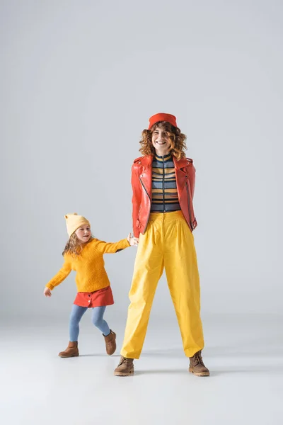 Mãe e filha em roupas coloridas vermelhas e amarelas no fundo cinza — Fotografia de Stock