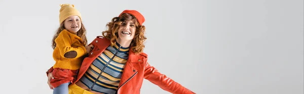 Mère et fille en tenues rouges et jaunes colorées isolées sur fond gris, panoramique — Photo de stock