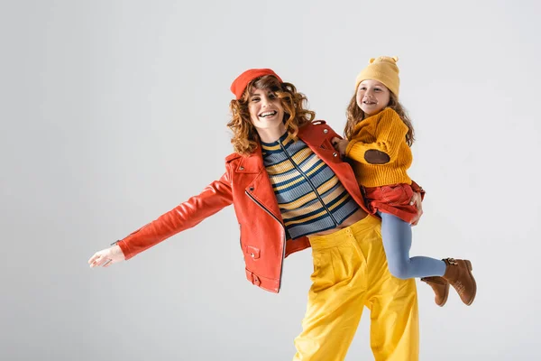 Mère et fille en tenues rouges et jaunes colorées isolées sur gris — Photo de stock