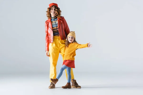 Mãe e filha em roupas coloridas vermelhas e amarelas no fundo cinza — Fotografia de Stock