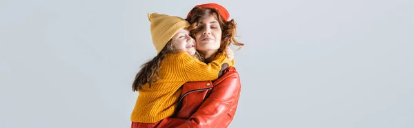 Mutter und Tochter in farbenfrohen roten und gelben Outfits umarmen sich vereinzelt auf grauen, panoramischen Aufnahmen — Stockfoto
