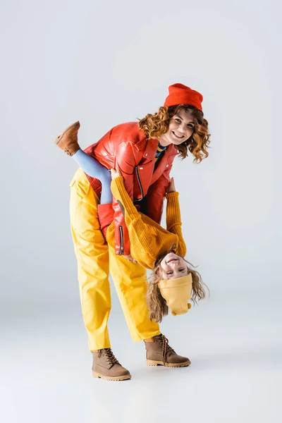 Mother and daughter in colorful red and yellow outfits playing on grey background — Stock Photo