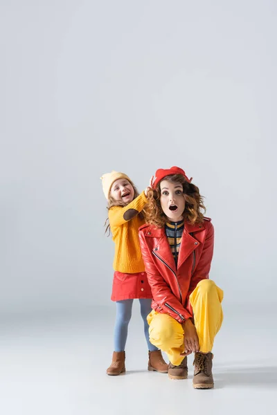 Mother and daughter in colorful red and yellow outfits having fun on grey background — Stock Photo