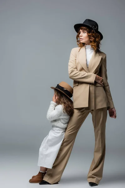 Elegant mother and daughter in white and beige outfits posing on grey — Stock Photo