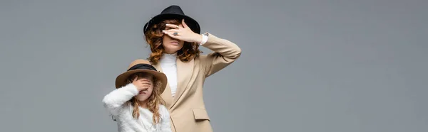 Elegante Mutter und Tochter in weißen und beigen Outfits, die Gesichter isoliert auf grauen, panoramischen Aufnahmen verdecken — Stockfoto