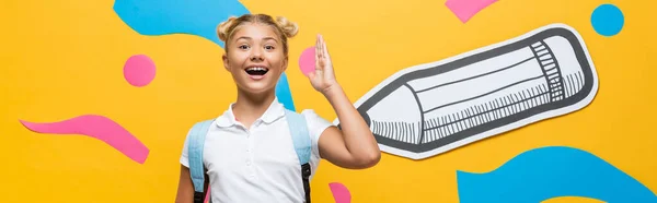 Website header of excited schoolgirl raising hand and looking at camera on yellow background with multicolored paper artwork — Stock Photo