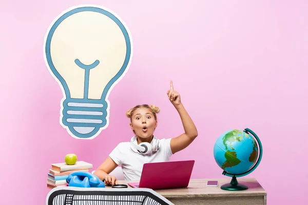 Excited schoolkid having idea near gadgets and paper artwork on pink background — Stock Photo