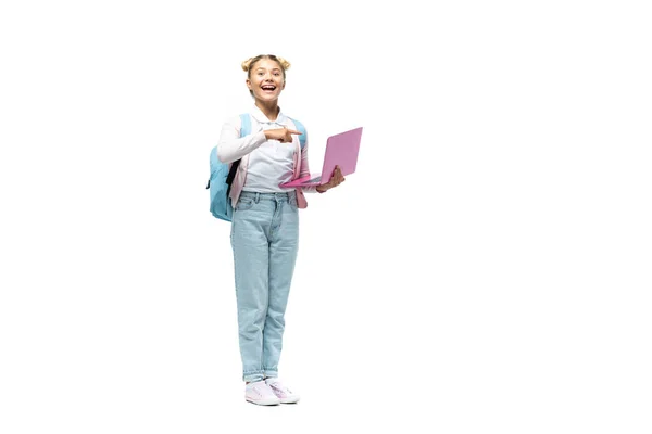 Excited schoolgirl pointing with finger at laptop on white background — Stock Photo