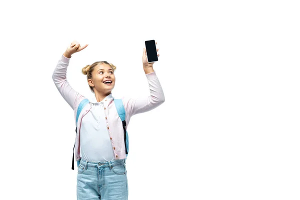 Menina com mochila apontando com o dedo para smartphone isolado no branco — Fotografia de Stock