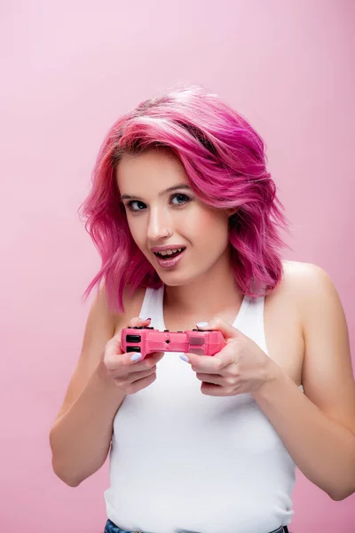КИІВ, УКРАЇН - 29 ЛИПНЯ 2020: молода жінка з барвистим волоссям, що тримає джойстик ізольований на рожевому — стокове фото