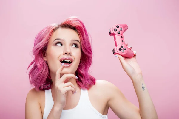 KYIV, UCRÂNIA - JULHO 29, 2020: jovem mulher com cabelo colorido olhando para joystick isolado em rosa — Fotografia de Stock
