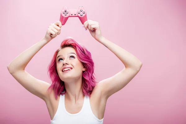 QUIIV, UCRÂNIA - JULHO 29, 2020: jovem com cabelo colorido segurando joystick acima da cabeça isolado em rosa — Fotografia de Stock