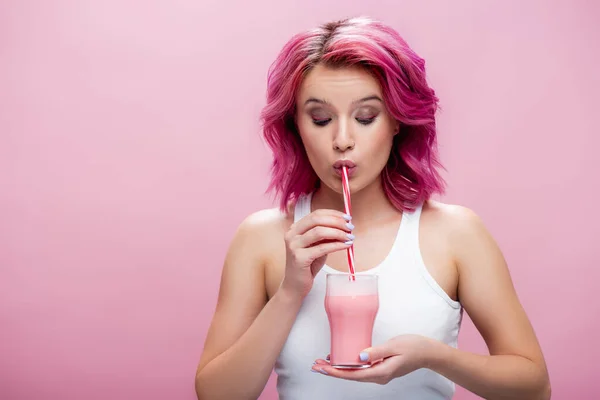 Jeune femme aux cheveux colorés boire milkshake fraise de paille isolé sur rose — Photo de stock