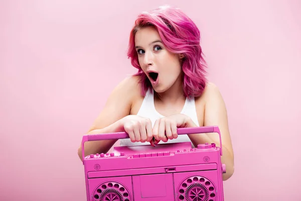 Shocked young woman with colorful hair holding painted tape recorder isolated on pink — Stock Photo