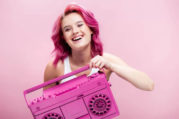 Mujer joven con pelo colorido sosteniendo grabadora de cinta pintada y sonriendo aislado en rosa - foto de stock