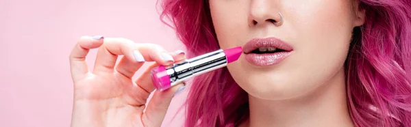 Cropped view of young woman with colorful hair holding lipstick isolated on pink, panoramic shot — Stock Photo