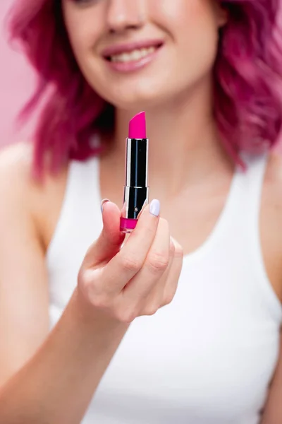 Selektiver Fokus der jungen Frau mit bunten Haaren, die Lippenstift isoliert auf rosa hält — Stockfoto