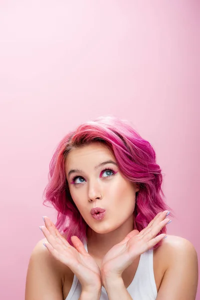 Здивована молода жінка з барвистим волоссям і макіяжем позує руками біля обличчя ізольовано на рожевому — стокове фото