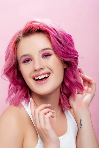 Молода жінка з барвистим волоссям і макіяжем посміхається ізольовано на рожевому — стокове фото