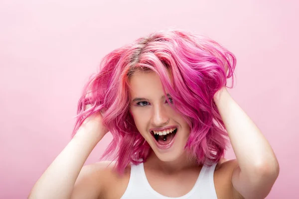 Mujer joven tocando pelo colorido aislado en rosa - foto de stock