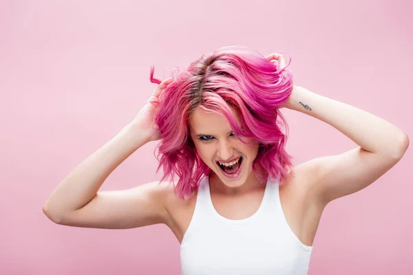 Aufgeregte junge Frau berührt bunte Haare isoliert auf rosa — Stockfoto