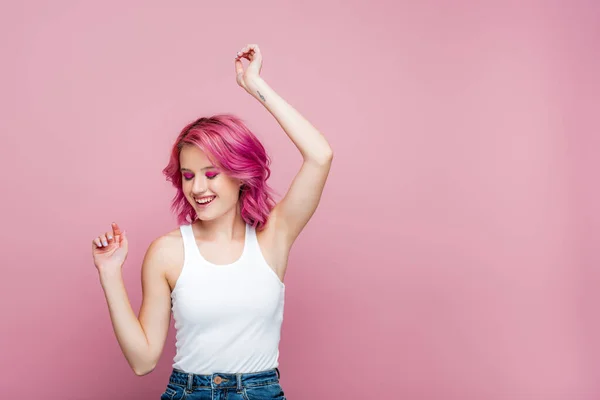 Mujer joven con el gesto de pelo colorido aislado en rosa - foto de stock