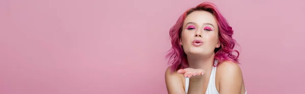 Giovane donna con capelli colorati soffiando bacio isolato su rosa, colpo panoramico — Foto stock