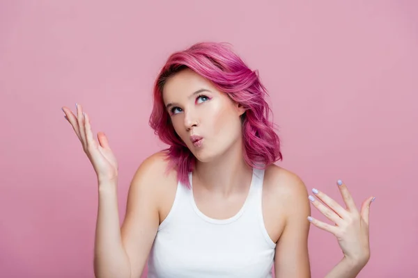 Young woman with colorful hair pouting lips and gesturing isolated on pink — Stock Photo