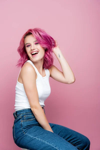 Mujer joven con pelo colorido y tatuaje sonriendo aislado en rosa - foto de stock