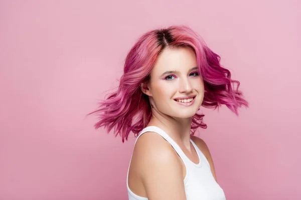 Mujer joven con el pelo colorido sonriendo aislado en rosa - foto de stock