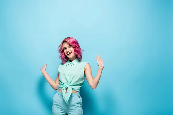 Young woman with pink hair gesturing on blue background — Stock Photo