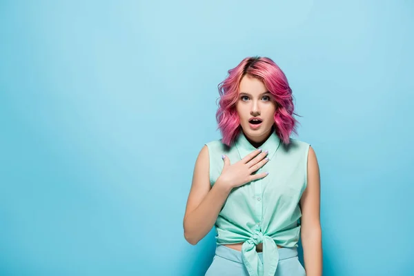 Surprised young woman with pink hair and open mouth on blue background — Stock Photo