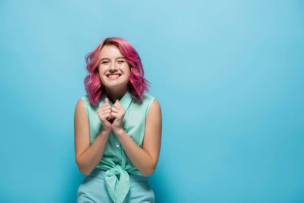 Jovem mulher com o cabelo rosa sorrindo no fundo azul — Fotografia de Stock