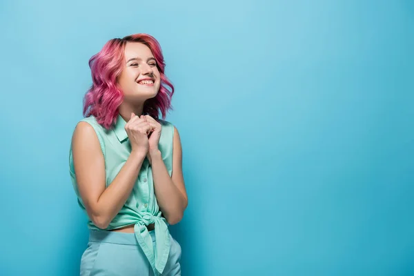 Jeune femme aux cheveux roses souriant sur fond bleu — Photo de stock