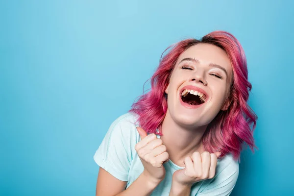 Junge Frau mit rosa Haaren lacht auf blauem Hintergrund — Stockfoto