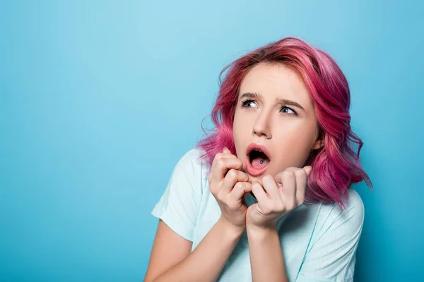 Scared young woman with pink hair on blue background — Stock Photo
